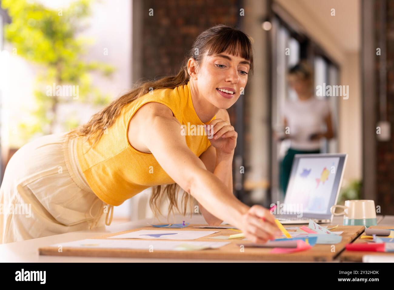 Im Büro, auf Haftnotizen schreiben, eine Frau, die Ideen am Schreibtisch mit Laptop erarbeitet Stockfoto