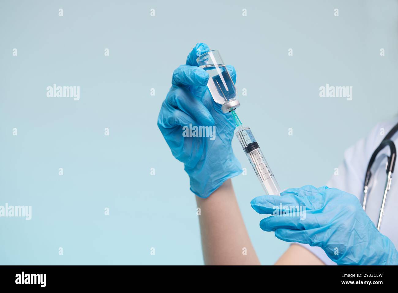 Die Hand des Arztes trägt einen medizinischen Handschuh, der eine Spritze hält, während er einen flüssigen Impfstoff aus einer Durchstechflasche nimmt, die gerade injiziert wird. Injektionsimpfung Stockfoto