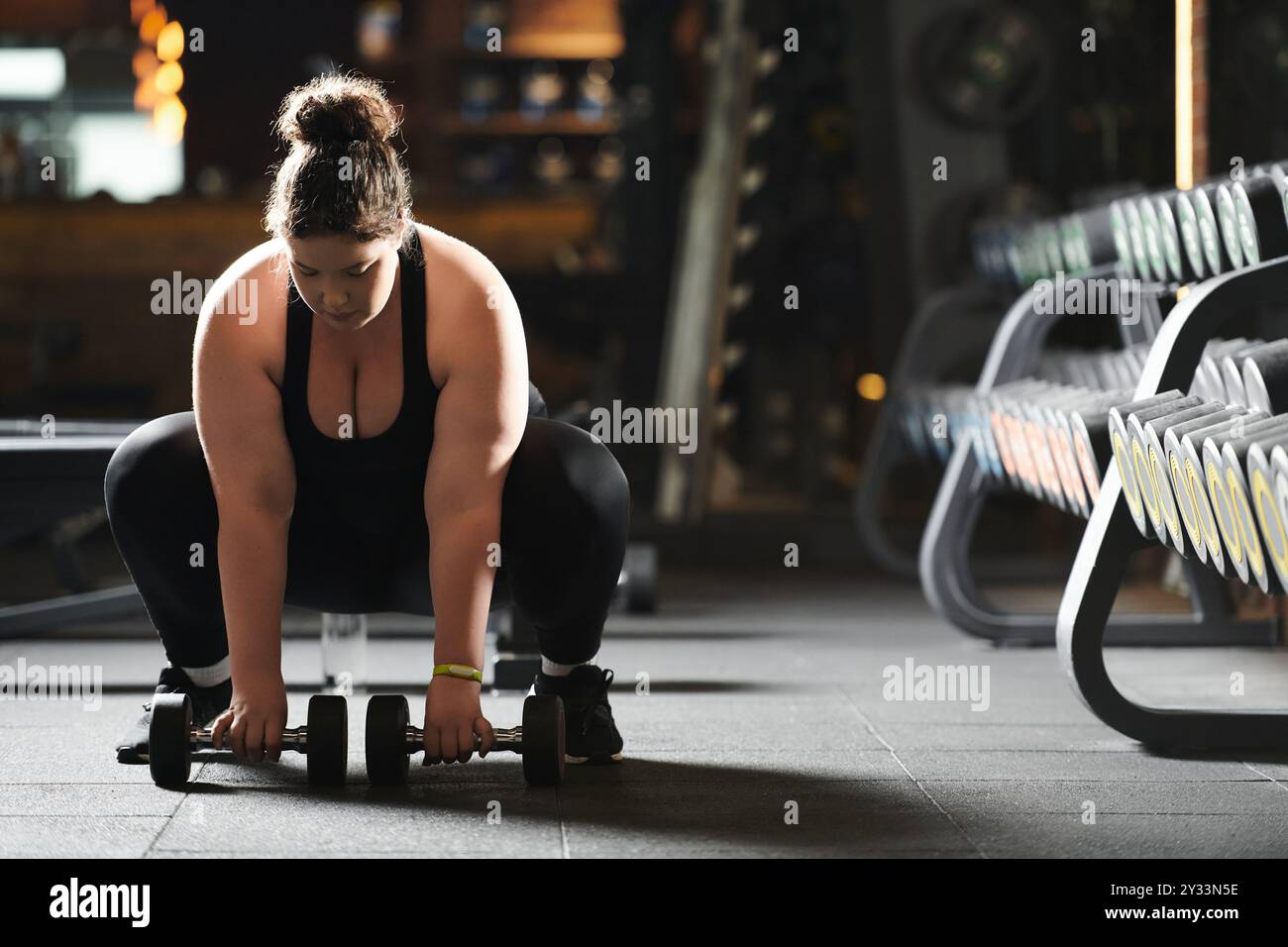 Eine selbstbewusste junge Frau begrüßt Körperpositivität beim Krafttraining mit Kurzhanteln. Stockfoto