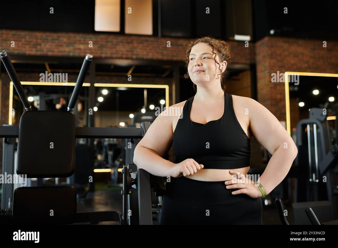 Eine junge Frau in Übergrößen-Übungen im Fitnessstudio, die ihren Körper und ihre Kraft feiert. Stockfoto