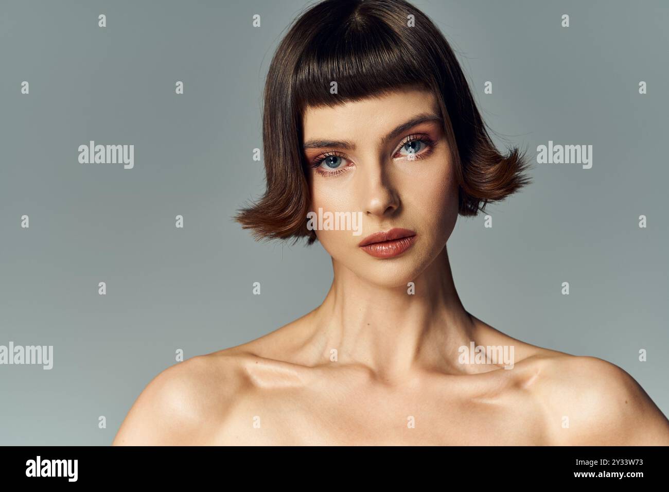 Eine schöne junge Frau zeigt ein kräftiges rotes Kleid mit einer großen Schleife und kurzen Haaren. Stockfoto