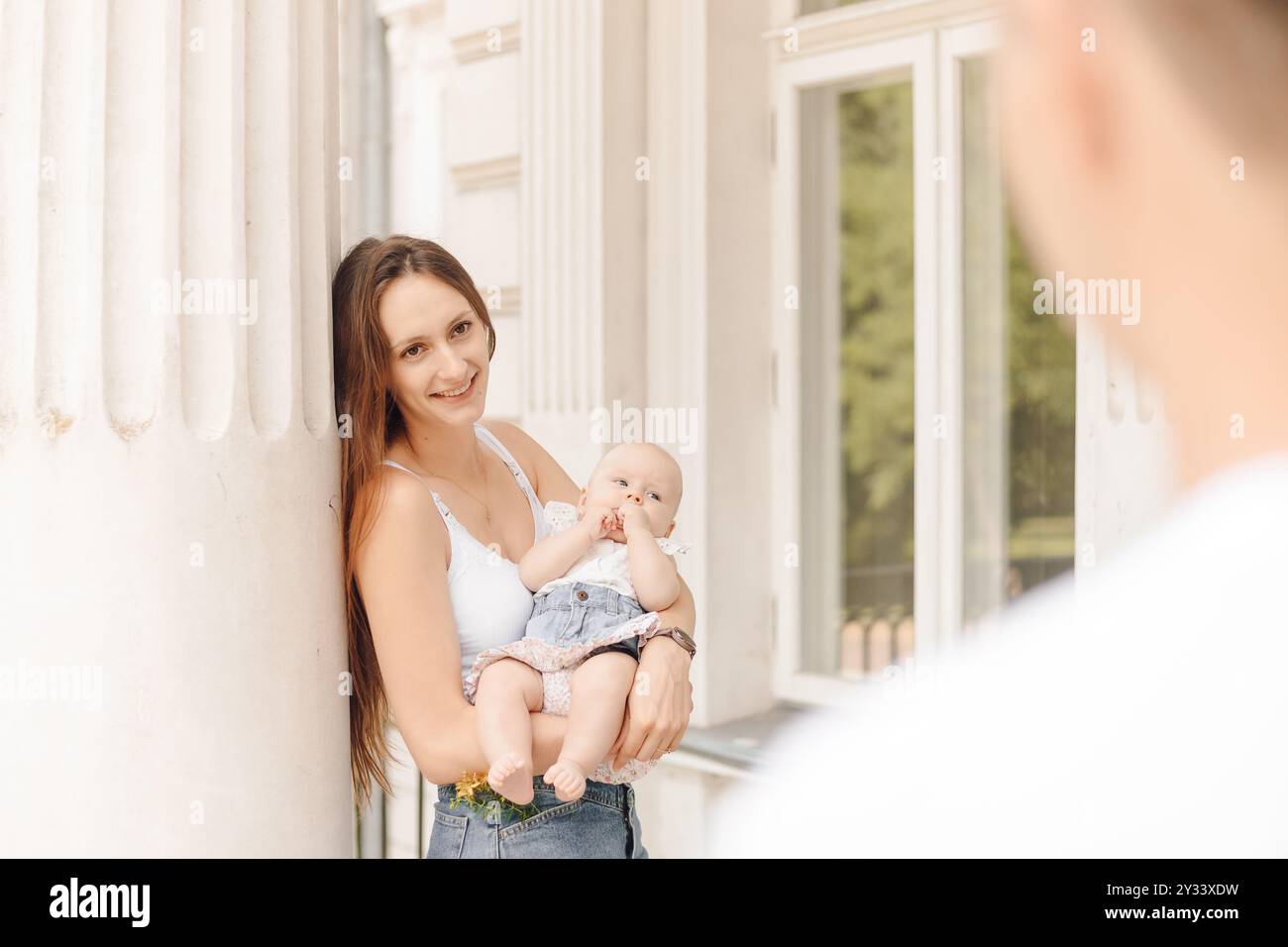 Eine Frau hält ein Baby in den Armen, während ein Mann zusieht Stockfoto