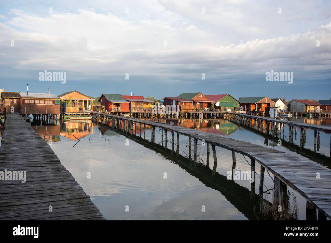 Oroszlany, Ungarn. September 2024. Reflexionen der Gebäude im Wasser und stürmische Wolken am frühen Morgen über dem schwimmenden Dorf Bokodi. Der Bodoki-See ist ein künstlicher See in Oroszlany, Ungarn. Sie wurde 1961 von der Oroszlany Thermal Power Company gegründet. Die Häuser stehen über dem Wasser auf Stelzen. Im Laufe der Jahre wurde der Bokodi-See zu einem beliebten Angelplatz und Ort für Fotografen. (Foto: Krisztian Elek/SOPA Images/SIPA USA) Credit: SIPA USA/Alamy Live News Stockfoto
