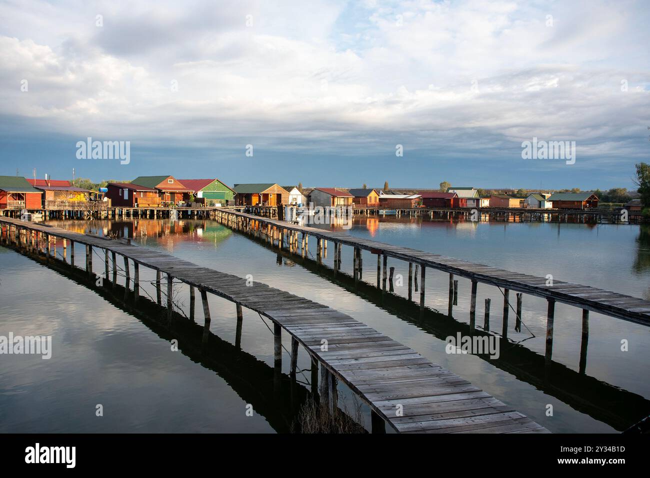 Oroszlany, Ungarn. September 2024. Reflexionen der Gebäude im Wasser und stürmische Wolken am frühen Morgen über dem schwimmenden Dorf Bokodi. Der Bodoki-See ist ein künstlicher See in Oroszlany, Ungarn. Sie wurde 1961 von der Oroszlany Thermal Power Company gegründet. Die Häuser stehen über dem Wasser auf Stelzen. Im Laufe der Jahre wurde der Bokodi-See zu einem beliebten Angelplatz und Ort für Fotografen. (Foto: Krisztian Elek/SOPA Images/SIPA USA) Credit: SIPA USA/Alamy Live News Stockfoto