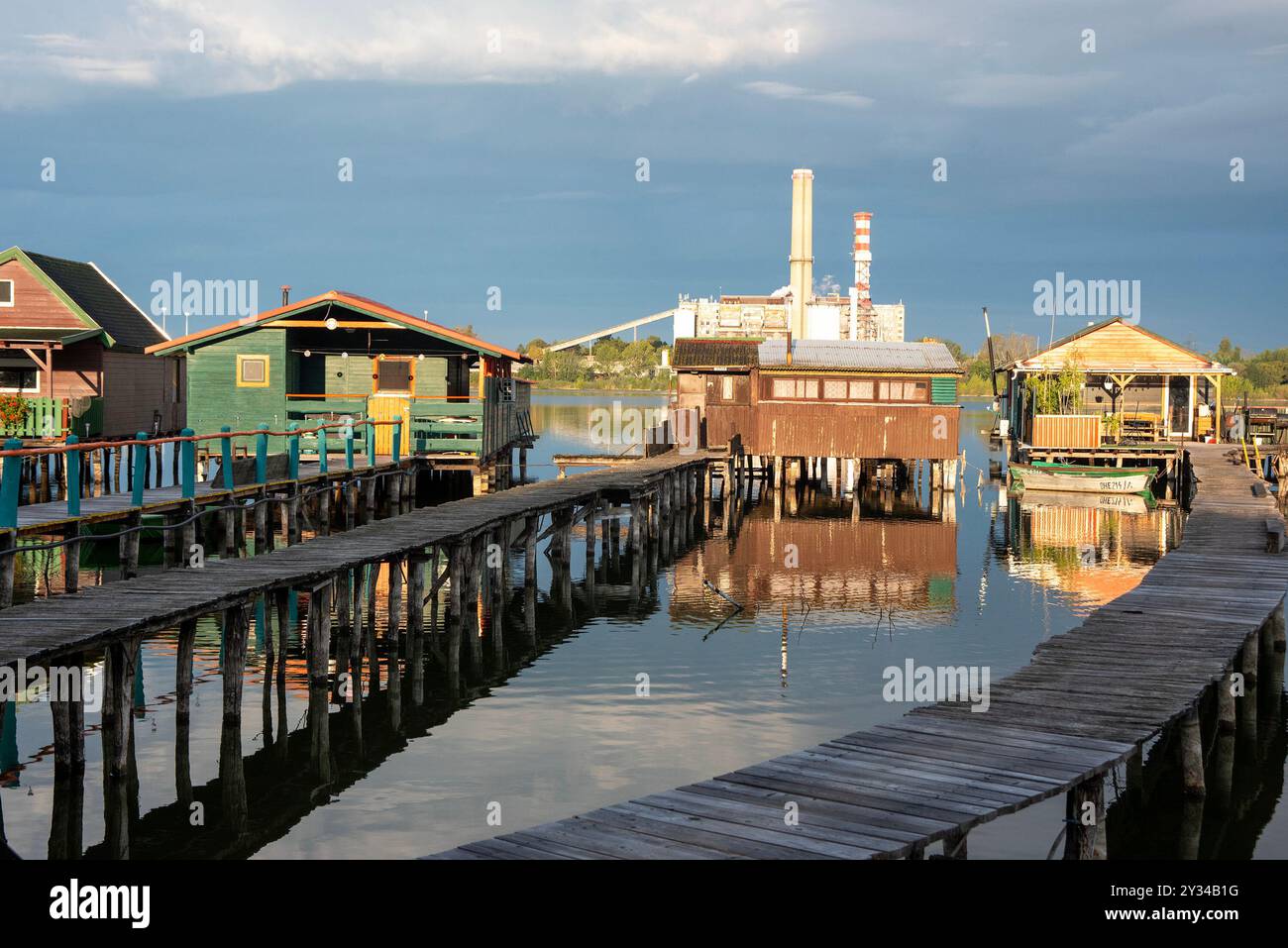 Oroszlany, Ungarn. September 2024. Reflexionen der Gebäude im Wasser und stürmische Wolken am frühen Morgen über dem schwimmenden Dorf Bokodi. Der Bodoki-See ist ein künstlicher See in Oroszlany, Ungarn. Sie wurde 1961 von der Oroszlany Thermal Power Company gegründet. Die Häuser stehen über dem Wasser auf Stelzen. Im Laufe der Jahre wurde der Bokodi-See zu einem beliebten Angelplatz und Ort für Fotografen. (Foto: Krisztian Elek/SOPA Images/SIPA USA) Credit: SIPA USA/Alamy Live News Stockfoto