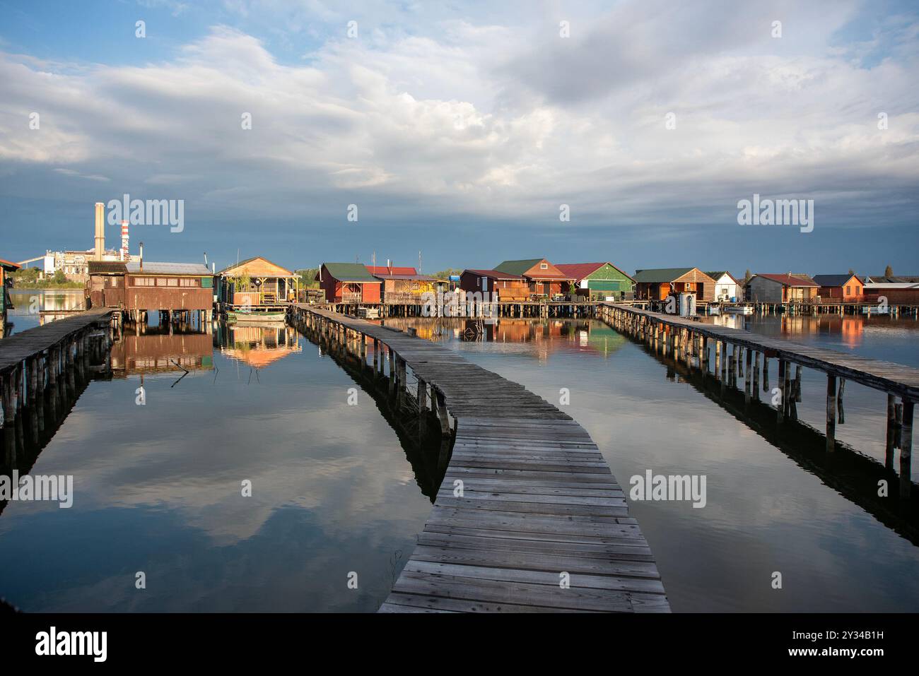 Oroszlany, Ungarn. September 2024. Reflexionen der Gebäude im Wasser und die stürmischen Wolken am frühen Morgen über dem schwimmenden Dorf Bokodi. Der Bodoki-See ist ein künstlicher See in Oroszlany, Ungarn. Sie wurde 1961 von der Oroszlany Thermal Power Company gegründet. Die Häuser stehen über dem Wasser auf Stelzen. Im Laufe der Jahre wurde der Bokodi-See zu einem beliebten Angelplatz und Ort für Fotografen. (Foto: Krisztian Elek/SOPA Images/SIPA USA) Credit: SIPA USA/Alamy Live News Stockfoto