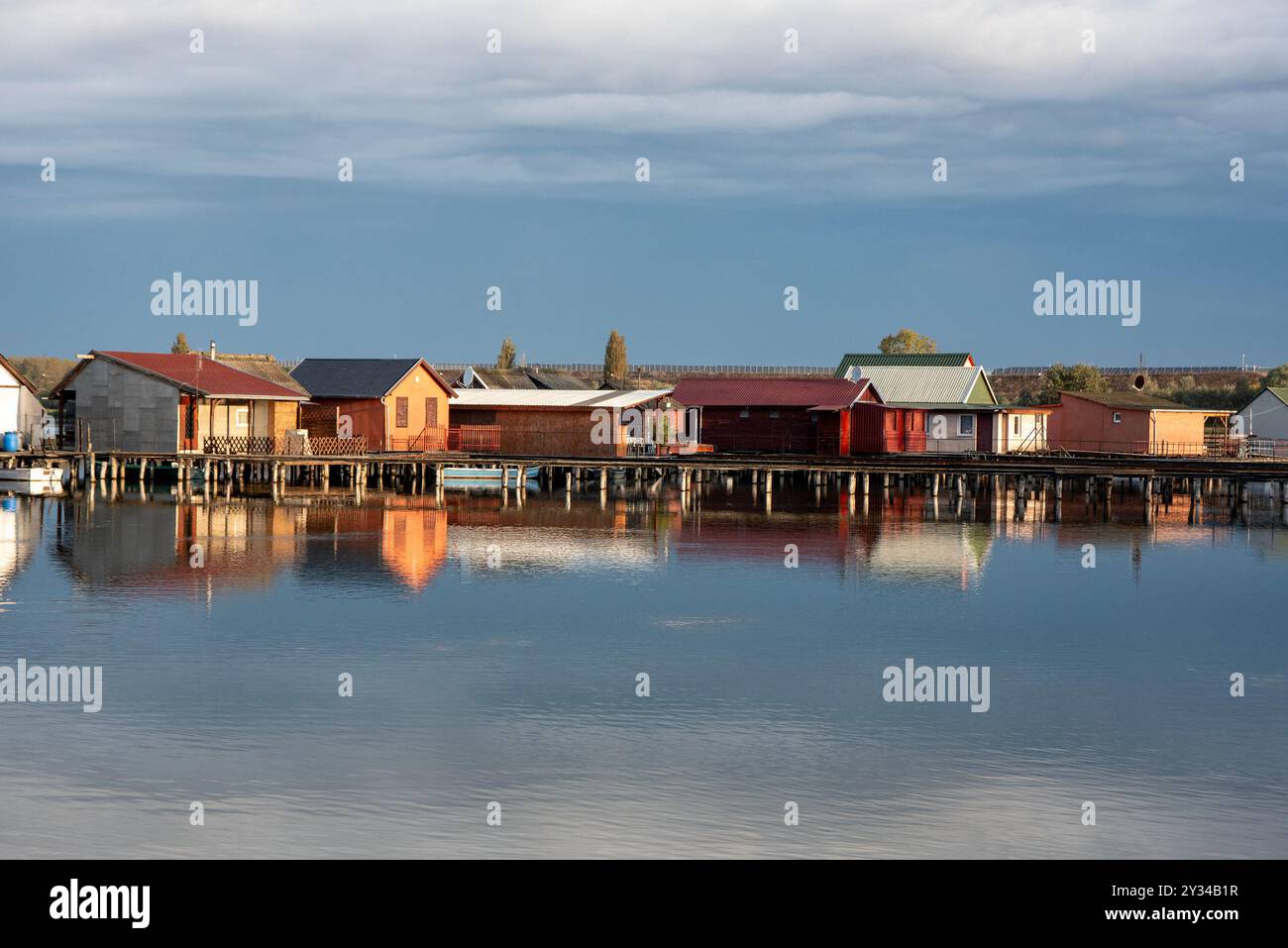 Oroszlany, Ungarn. September 2024. Reflexionen der Gebäude am Bokodi-See, Ungarn. Der Bodoki-See ist ein künstlicher See in Oroszlany, Ungarn. Sie wurde 1961 von der Oroszlany Thermal Power Company gegründet. Die Häuser stehen über dem Wasser auf Stelzen. Im Laufe der Jahre wurde der Bokodi-See zu einem beliebten Angelplatz und Ort für Fotografen. (Foto: Krisztian Elek/SOPA Images/SIPA USA) Credit: SIPA USA/Alamy Live News Stockfoto