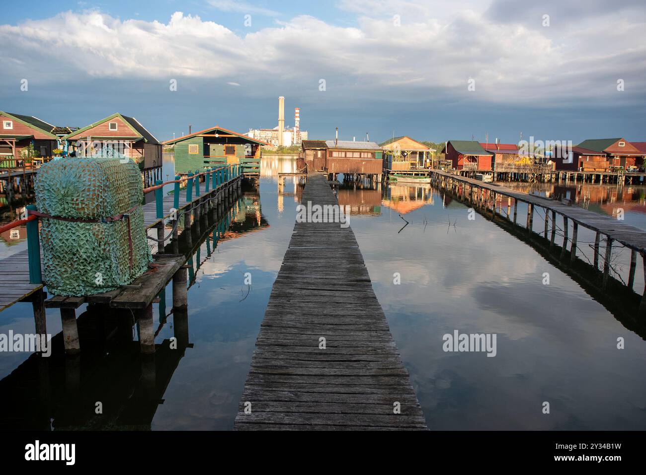 Oroszlany, Ungarn. September 2024. Reflexionen der Gebäude im Wasser und stürmische Wolken am frühen Morgen über dem schwimmenden Dorf Bokodi. Der Bodoki-See ist ein künstlicher See in Oroszlany, Ungarn. Sie wurde 1961 von der Oroszlany Thermal Power Company gegründet. Die Häuser stehen über dem Wasser auf Stelzen. Im Laufe der Jahre wurde der Bokodi-See zu einem beliebten Angelplatz und Ort für Fotografen. (Foto: Krisztian Elek/SOPA Images/SIPA USA) Credit: SIPA USA/Alamy Live News Stockfoto