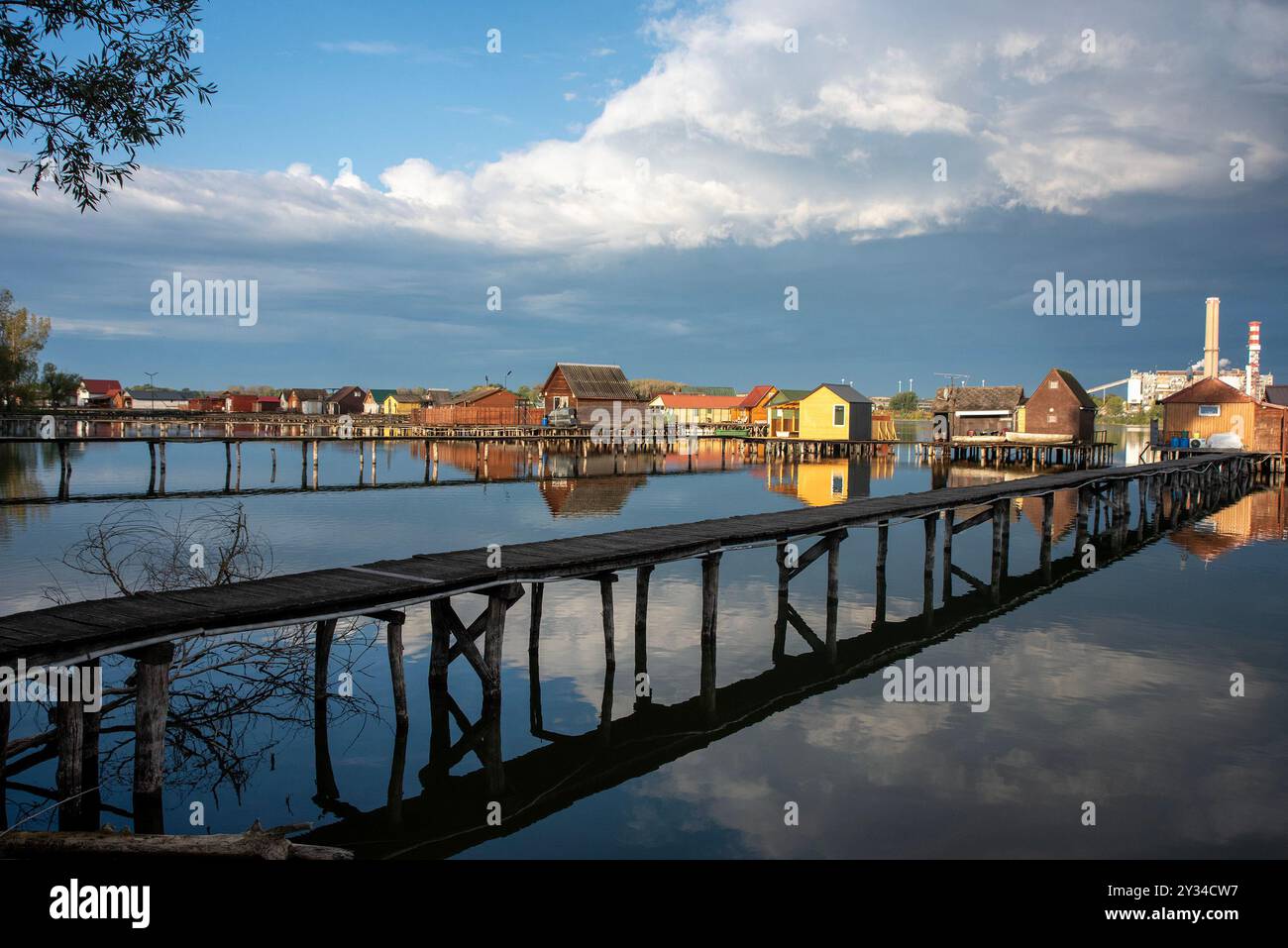 Oroszlany, Ungarn. September 2024. Reflexionen der Gebäude im Wasser und stürmische Wolken am frühen Morgen über dem schwimmenden Dorf Bokodi. Der Bodoki-See ist ein künstlicher See in Oroszlany, Ungarn. Sie wurde 1961 von der Oroszlany Thermal Power Company gegründet. Die Häuser stehen über dem Wasser auf Stelzen. Im Laufe der Jahre wurde der Bokodi-See zu einem beliebten Angelplatz und Ort für Fotografen. Quelle: SOPA Images Limited/Alamy Live News Stockfoto