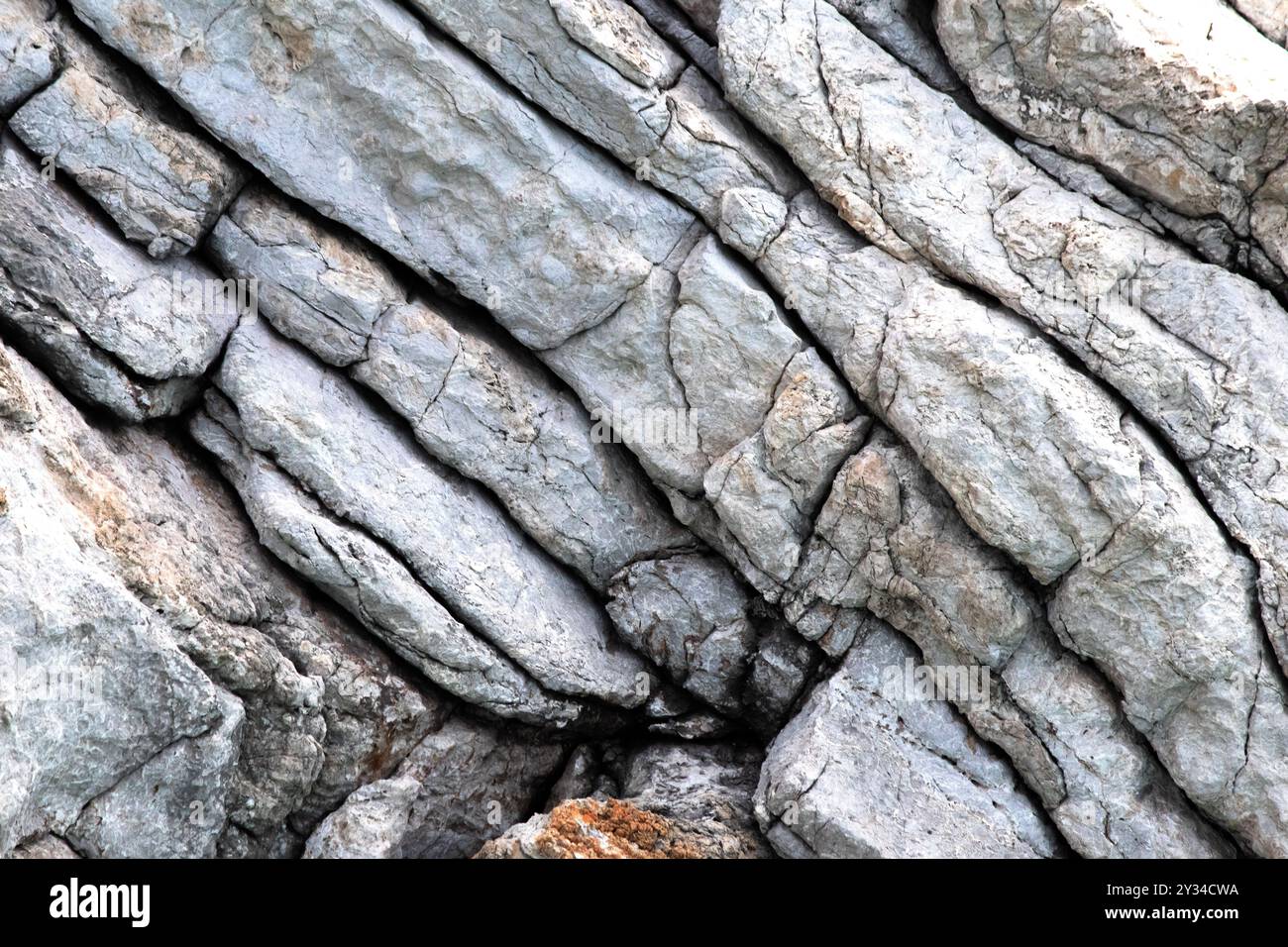 Die Steinmauer ist dicht mit Schichten von Gesteinsformationen. Natürliche Hintergrundbilder. Klippe. Muster. Horizontales Foto. Keine Menschen, niemand. Stockfoto