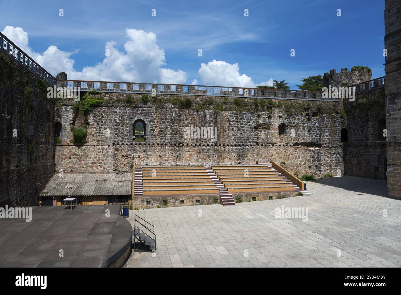 Innenhof eines historischen Schlosses mit Steinmauern und hölzernen Sitzreihen unter klarem blauen Himmel, Schloss, Castillo de la Triste Condesa, Arenas de San P Stockfoto