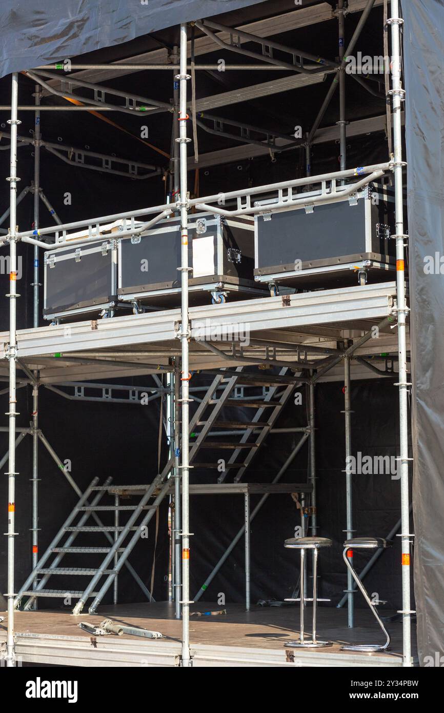 An einem Veranstaltungsort im Freien werden zahlreiche Ton- und Beleuchtungsgeräte für ein Konzert aufgestellt. Die Metallrahmen und -Gehäuse erzeugen eine dynamische Szene o Stockfoto