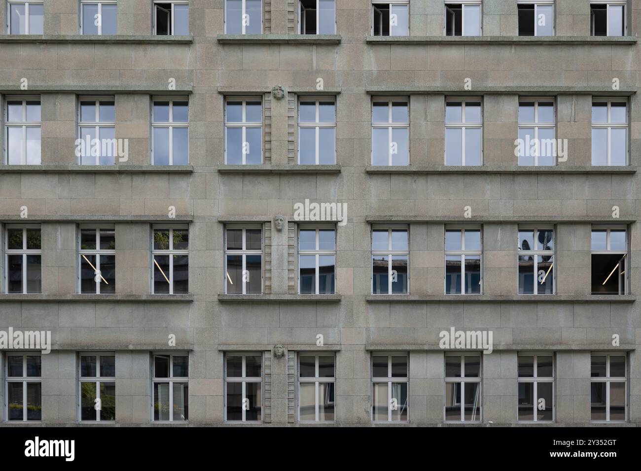 Düstere, graue, moderne Gebäudefassade mit hohen Fenstern. Direkt im Blick, keine Leute. Stockfoto