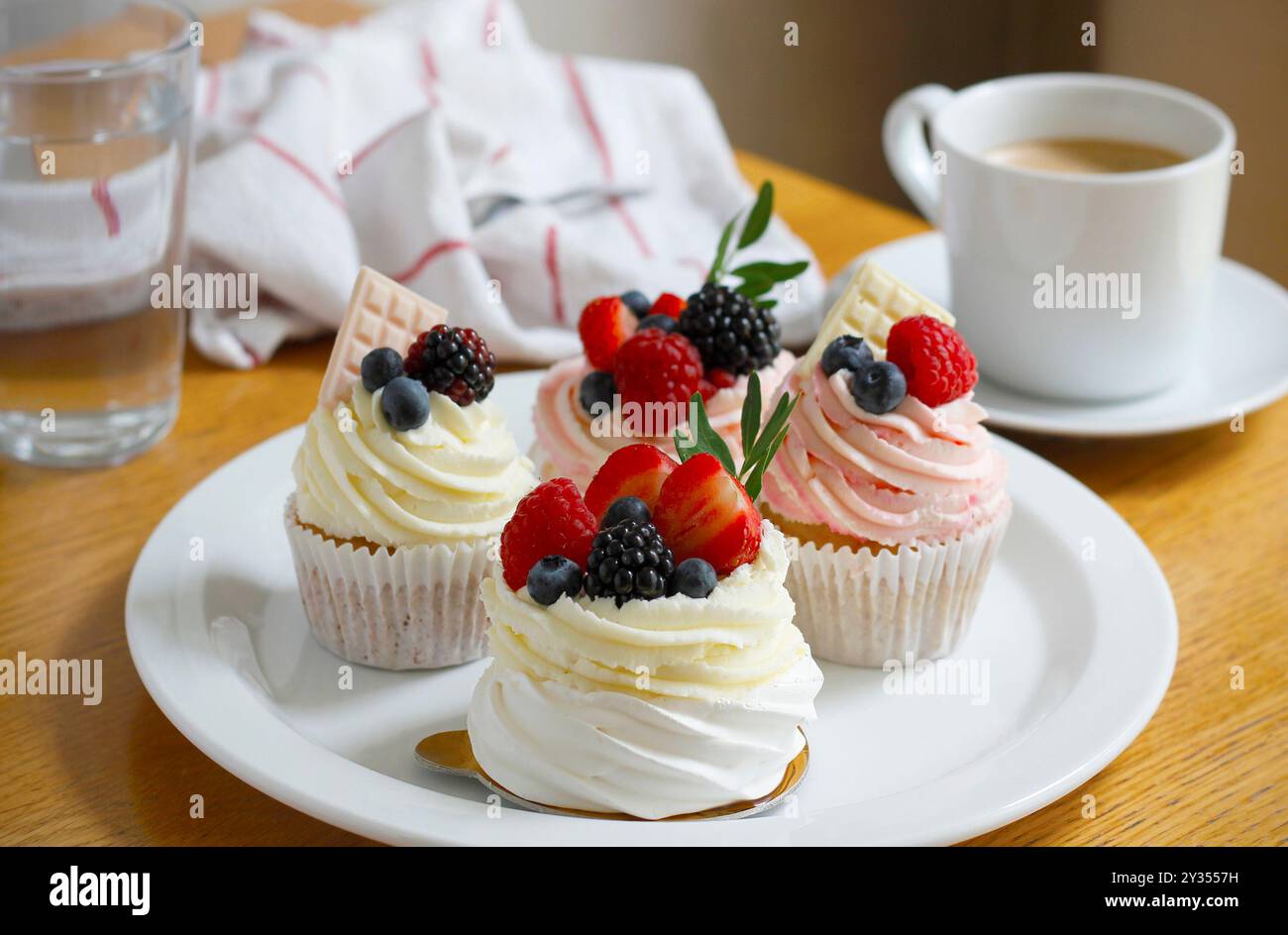 Cupcakes und Mini-pavlova-Kuchen, dekoriert mit frischen Beeren und weißer Schokolade Stockfoto