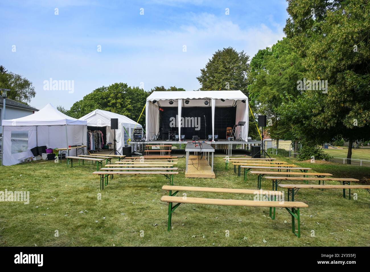 Freilichtbühne, Zelte für technische Ausstattung und als Umkleidekabine, Holzbänke für das Publikum, installiert auf einer Wiese für ein Musikfestival-Event Stockfoto