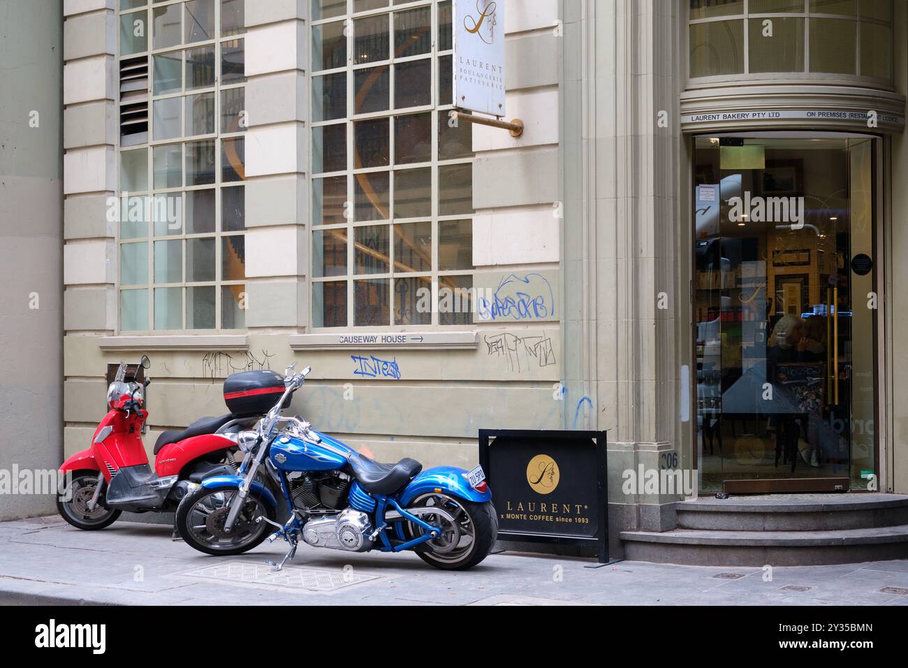 Laurent Boulangerie Patisserie oder Laurent Bakery in der Little Collins Street, mit Harley Davidson Motorrad und Scarabeo Scooter, Melbourne CBD. Stockfoto