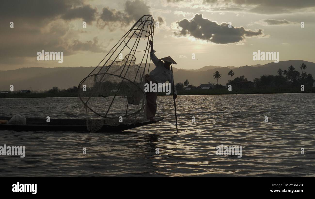 Fisherman Balancing auf dem Boot am Inle Lake, Myanmar bei Sundown Stockfoto