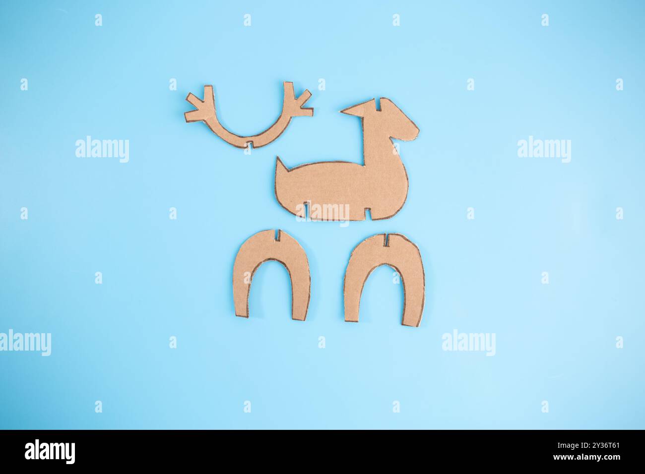 Braune Kartonformen für Rentierboote auf blauem Hintergrund. Perfektes Beispiel für die Umnutzung von Materialien in dekorative, umweltfreundliche Projekte, hoch Stockfoto
