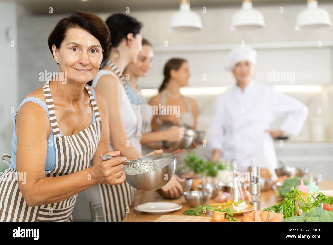 Während des Studiums in einem kulinarischen Workshop kocht die Dame appetitliche Soße, Marinade und Teig in einer Schüssel. Stockfoto