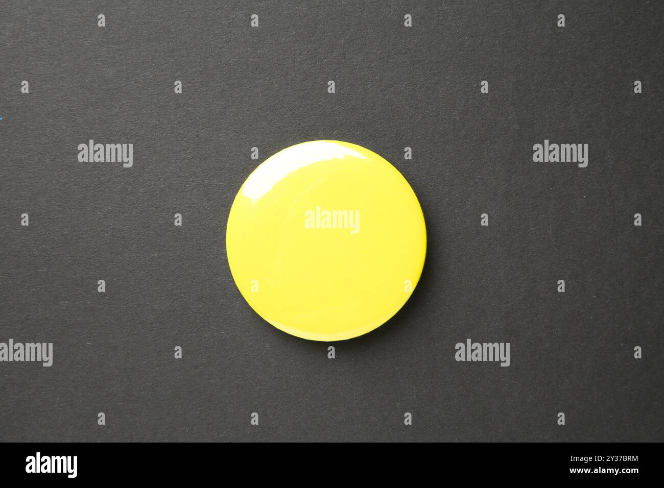 Leeres gelbes Knopfabzeichen auf schwarzem Hintergrund, Draufsicht. Modell für Design Stockfoto