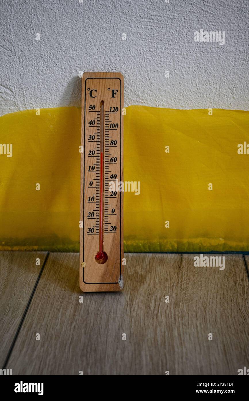 Auf dem Boden steht ein Holzthermometer, das eine hohe Raumtemperatur anzeigt. Stockfoto