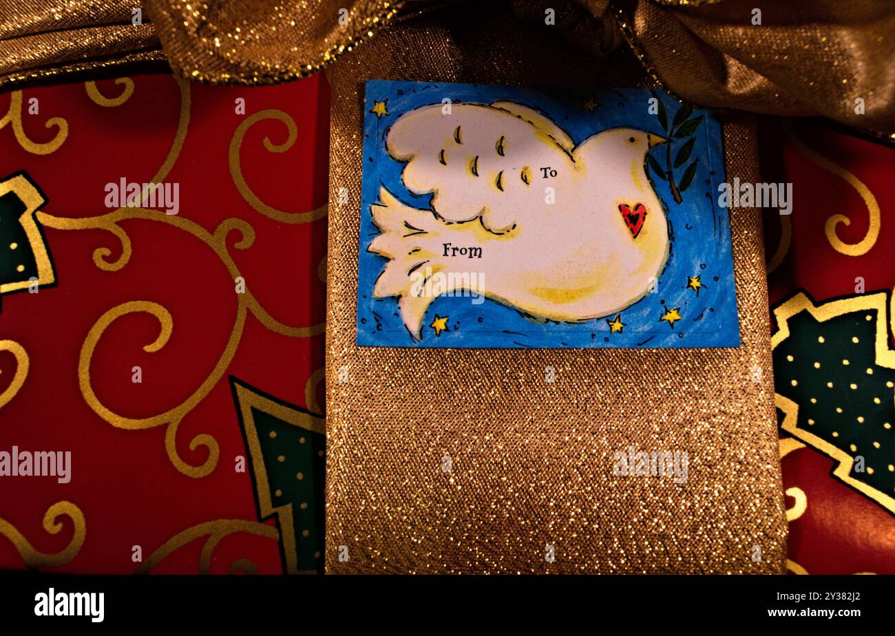 Ein rotes Weihnachtsgeschenk mit goldenem Band und blauem Geschenkanhänger. Stockfoto