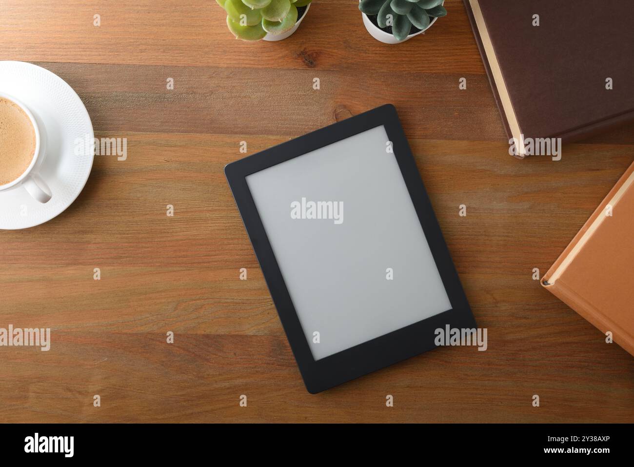 EBook auf Holztisch mit Papierbüchern, Kaffee und Pflanzen. Draufsicht Stockfoto