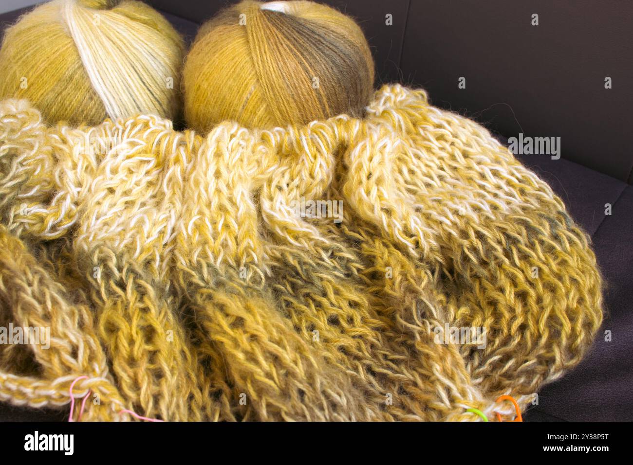 Verlaufsfarbene Garnkugel mit Strickjacke und Stricknadeln. Zitronenfarbene Alpaka- und Wollfäden mit wunderschönem Strickmuster. Stockfoto