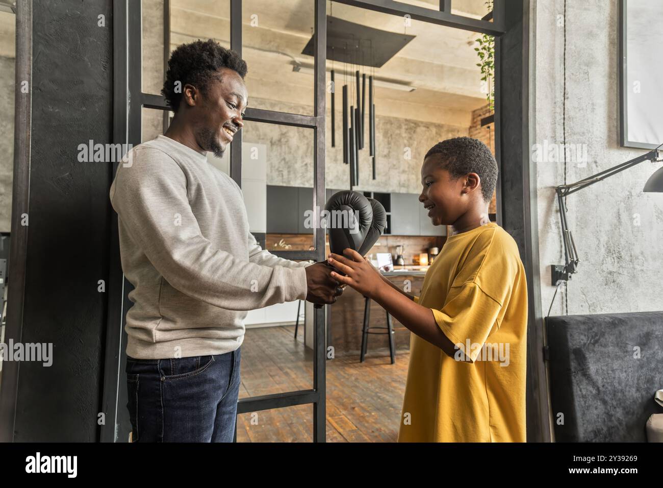 Ein Afroamerikaner gibt seinem Sohn Boxhandschuhe als Überraschungsgeschenk Stockfoto