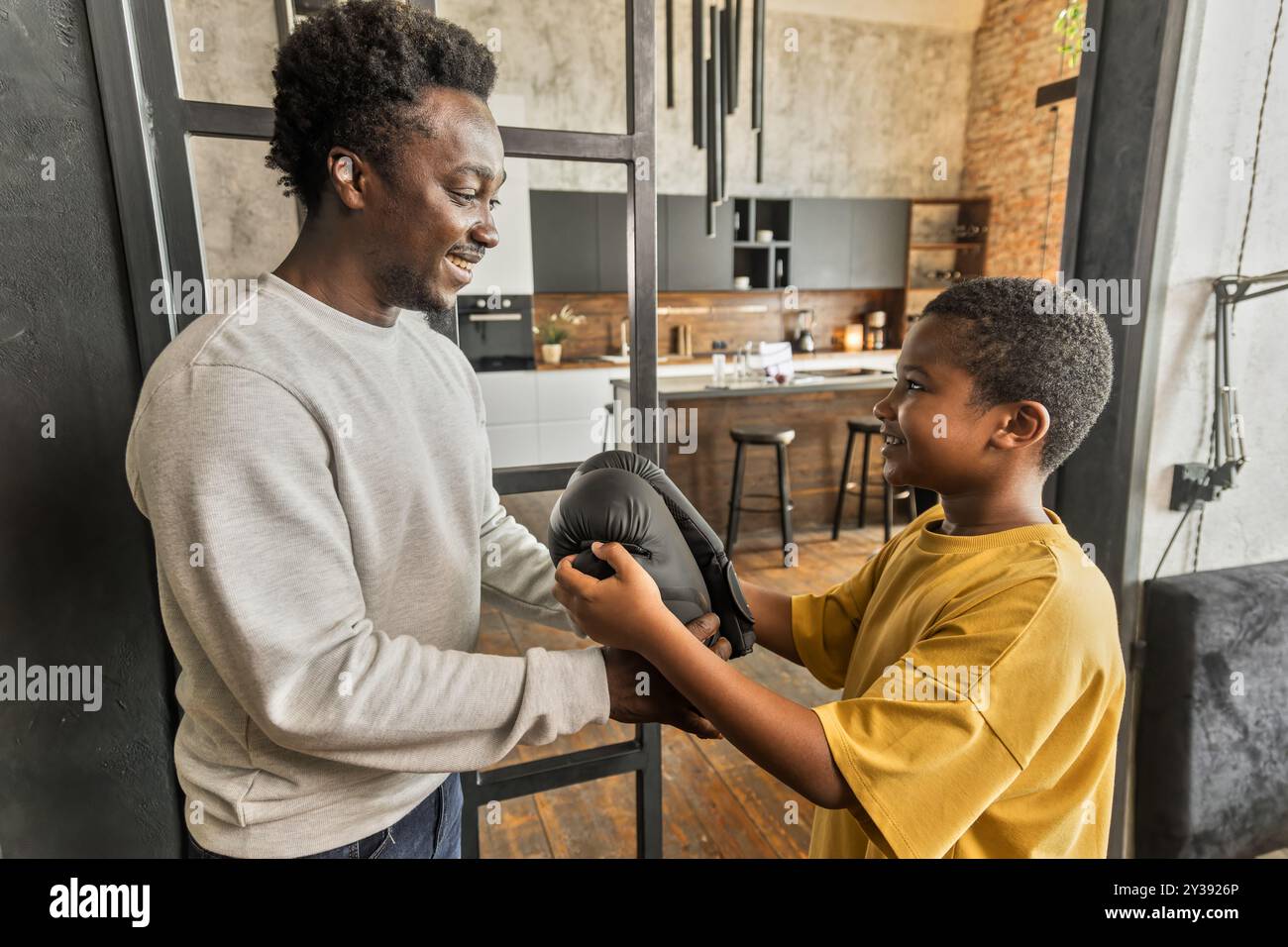 Ein Afroamerikaner gibt seinem Sohn Boxhandschuhe als Überraschungsgeschenk Stockfoto