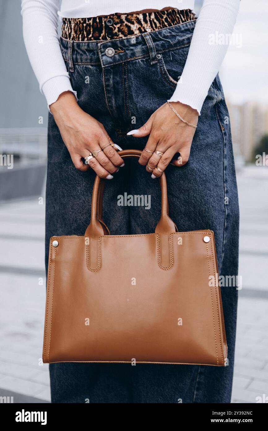 Ein Mädchen in Jeans, mit gebräunter Haut, hält einen Beutel in der Hand Stockfoto