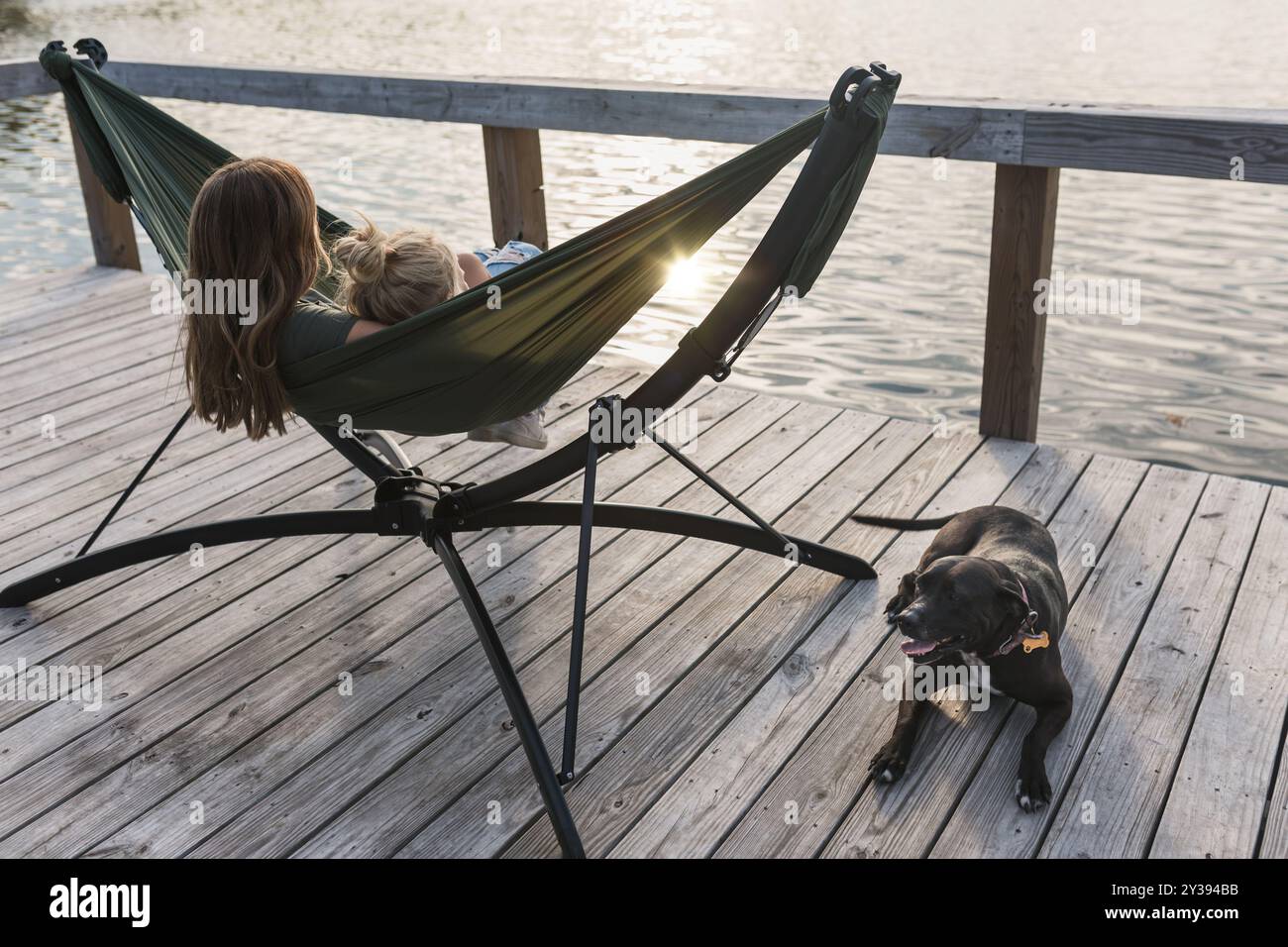 Die Leute entspannen sich in einer Hängematte am See mit einem Hund in der Nähe Stockfoto