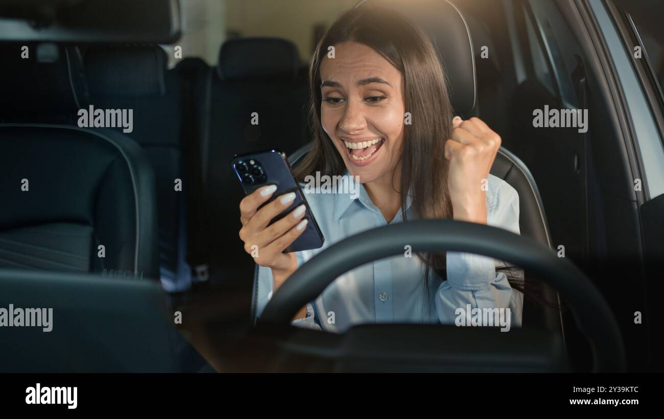 Kaukasische Geschäftsfrau glücklich aufgeregtes Mädchen Geschäftsfrau erfolgreiche Gewinnerin weibliche Fahrerin im Auto Auto Auto gewinnen Handy Erfolg Erfolg Erfolg Erfolg Erfolg Stockfoto
