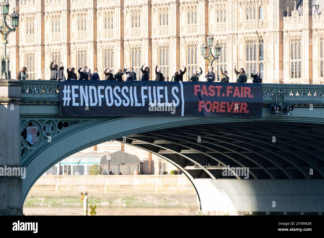 London, Großbritannien. 13. September 2024. Über der Westminster Bridge, von den Houses of Parliament, wird ein großes Banner geworfen, auf dem erklärt wird, dass es die größte globale Aktion überhaupt ist, um von den Regierungen zu fordern, dass sie daran arbeiten, die Verwendung fossiler Brennstoffe zu beenden. In der Aktionswoche vom 13. Bis 20. September wird die Kampagne „Global Fight to End fossile Brennstoffe“ mit der Kampagne „Pay Up for Climate Finance“ zusammengeführt, um einen gerechten und gerechten Ausstieg aus fossilen Brennstoffen als notwendiges Mittel zur Bekämpfung der Bedrohungen durch die globale Heizung zu fordern. Quelle: Ron Fassbender/Alamy Live News Stockfoto