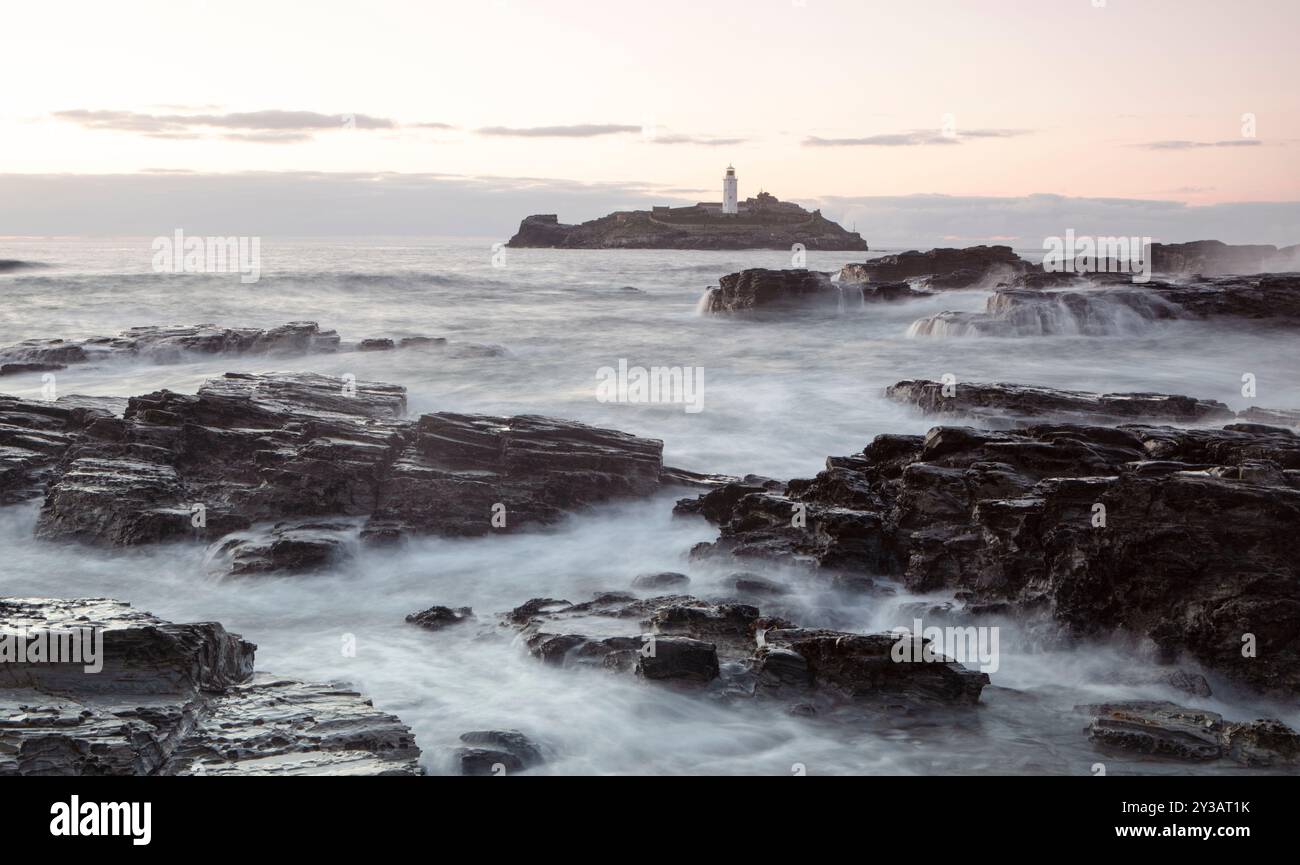 Ein Teil der Küste von Cornwall bei Ebbe mit Godrey Lighthouse im Hintergrund. Stockfoto