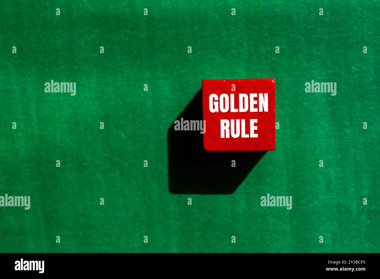 Goldene Regelbotschaft auf rotem Holzwürfel mit grünem Hintergrund. Konzeptionelles goldenes Regelsymbol. Kopierbereich. Stockfoto