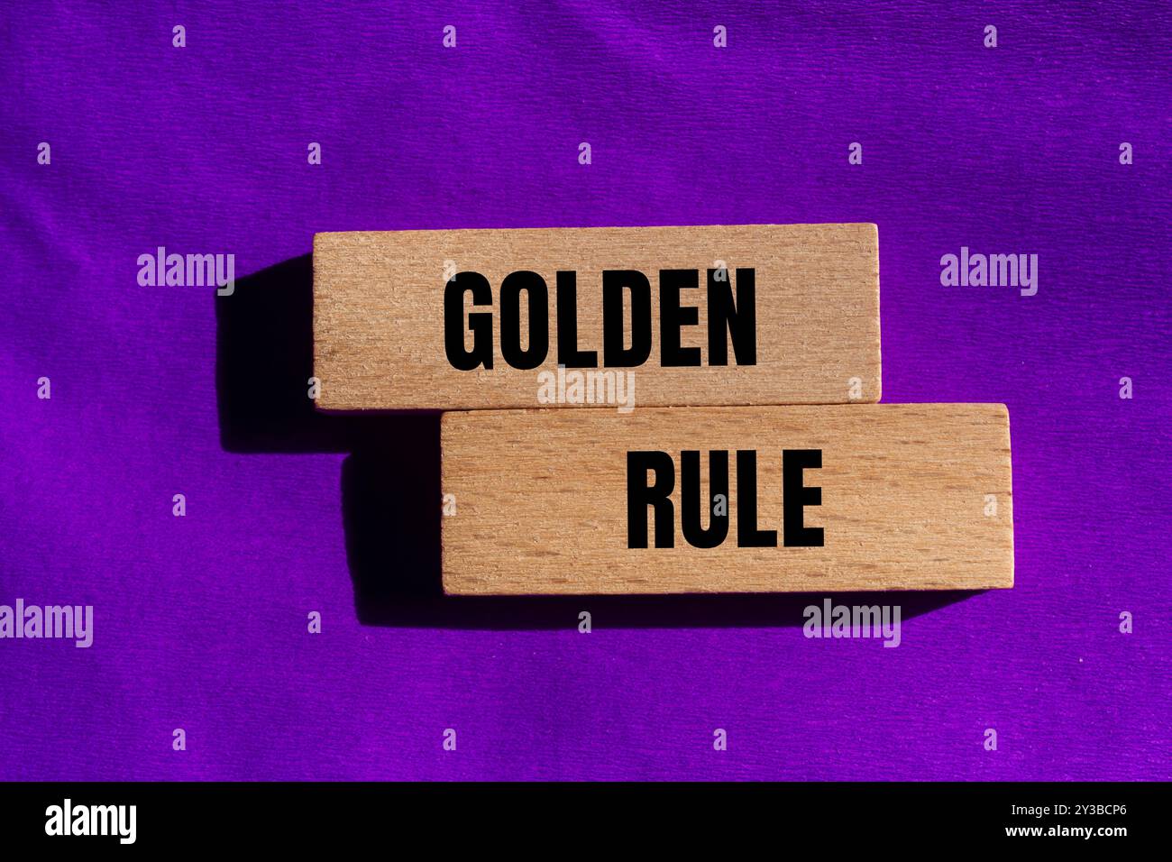 Goldene Regel-Nachricht auf Holzblöcken mit violettem Hintergrund. Konzeptionelles goldenes Regelsymbol. Kopierbereich. Stockfoto