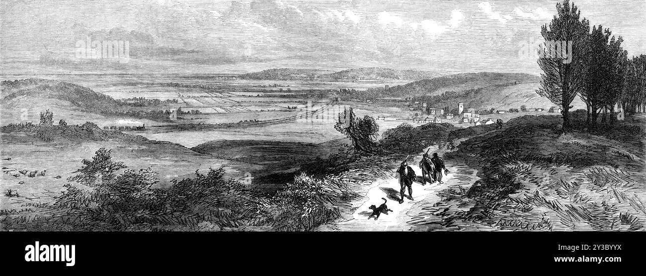 Blick in die Nähe von Sandringham, Blick in nordwestlicher Richtung nach Dersingham und der Eisenbahn in Wolferton, 1871. Die Landschaft um Sandringham in Norfolk, eine der Residenzen der britischen Königsfamilie, sah '...from den Park oder die Gärten von Sandringham, mit Blick nach Nordwesten - das heißt, auf der anderen Seite der Bahnlinie und in Richtung Wasch. Das Dorf auf der rechten Seite ist Dersingham, zu dem der Zug vom Bahnhof Wolferton kommt. Diese beiden Orte liegen auf dem Boden unterhalb der hügeligen Hügel von Sandringham, die aus Drift oder Kies bestehen und die ursprünglich bo gewesen sein müssen Stockfoto