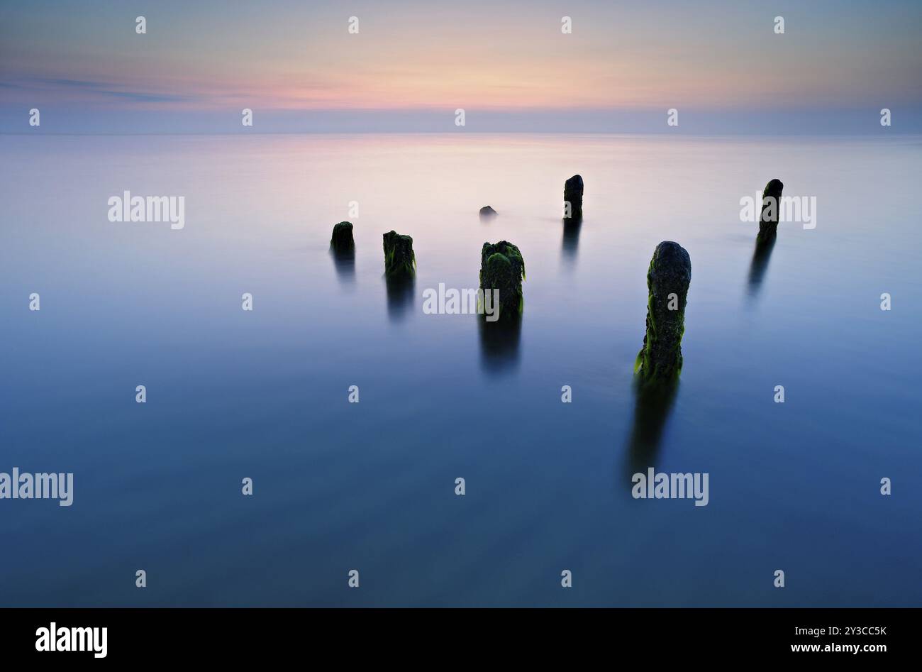 Alte Pfosten mit Algen im Wasser am Ostseestrand, lange Exposition bei Sonnenuntergang, Halbinsel Fischland-Darss-Zingst, Vorpommern Lagune Nationa Stockfoto