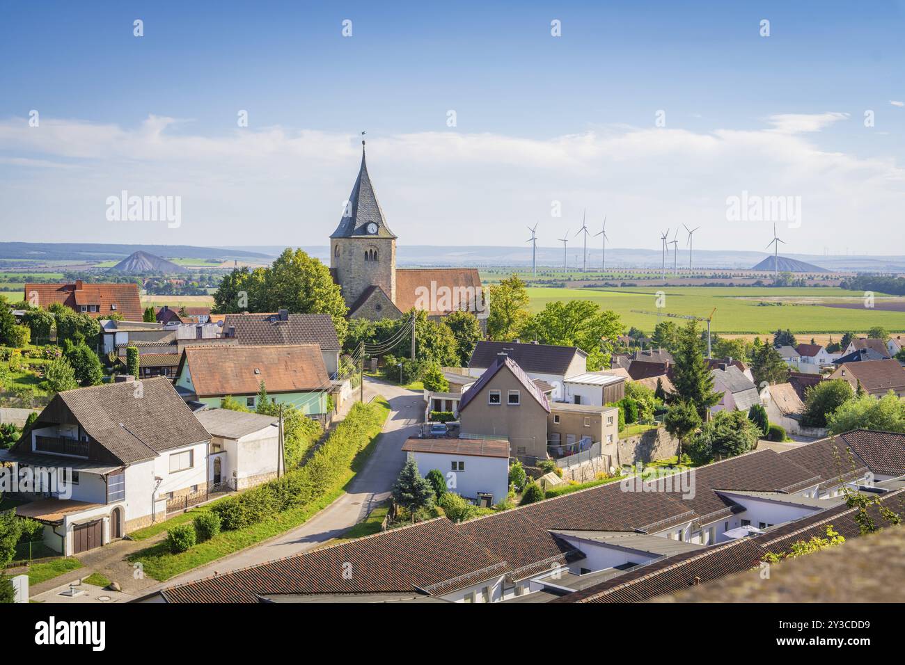 Ein friedliches Dorf mit einer Kirche im Vordergrund und Windrädern in der Ferne, Harz, Deutschland, Europa Stockfoto