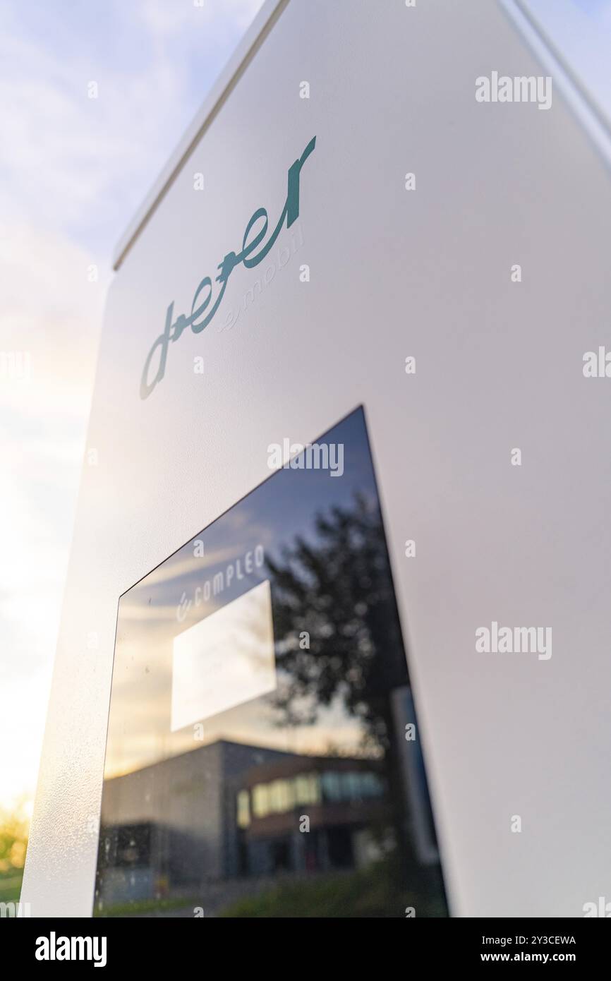 Nahaufnahme einer Ladestation mit reflektierendem Bildschirm und einem modernen Gebäude im Hintergrund, Calw, Schwarzwald, Deutschland, Europa Stockfoto