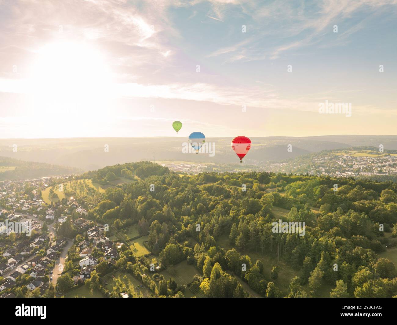 Blick auf mehrere Heißluftballons über einer bewaldeten Landschaft bei Sonnenuntergang in der Nähe einer Stadt, Calw, Schwarzwald, Deutschland, Europa Stockfoto