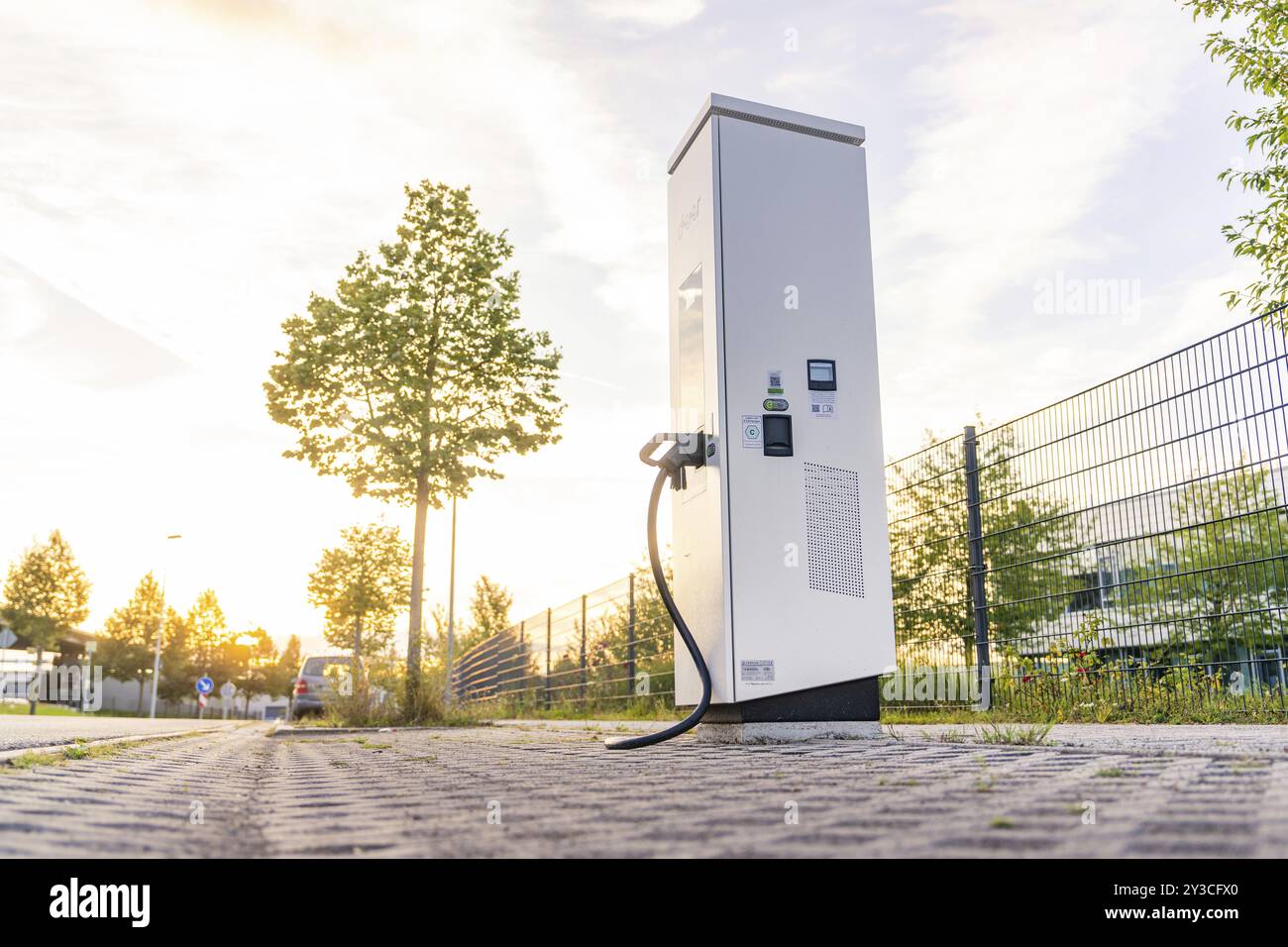 Eine elektrische Ladestation auf einer Kopfsteinpflasterstraße bei Sonnenuntergang, umgeben von Bäumen und städtischer Umgebung, Calw, Schwarzwald, Deutschland, Europa Stockfoto