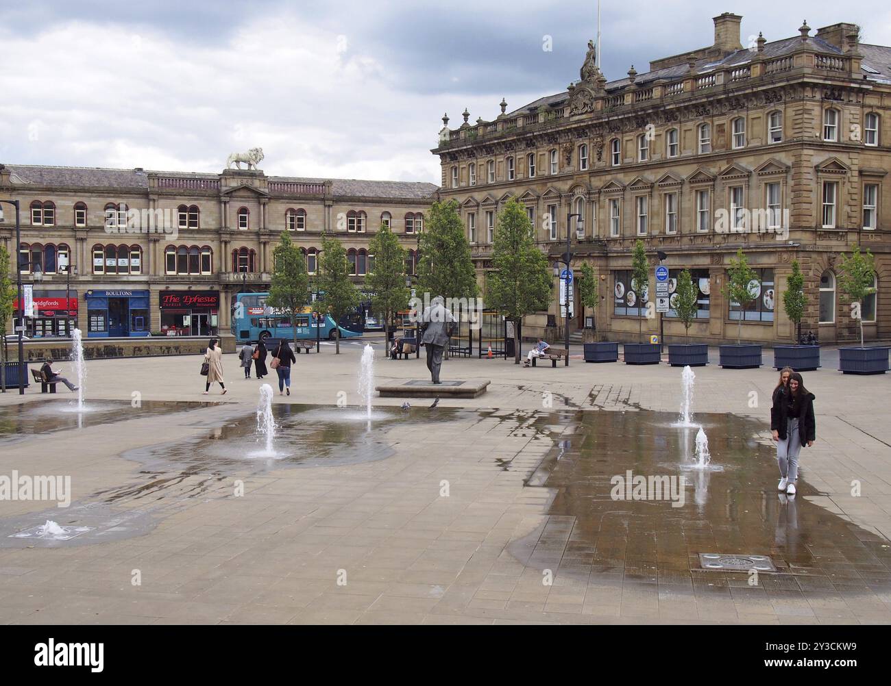 Huddersfield, Yest yorkshire, Vereinigtes Königreich, 20. Mai 2019: Menschen gehen auf dem St georges Square in Huddersfield zwischen den Wasserfontänen und der Umgebung Stockfoto