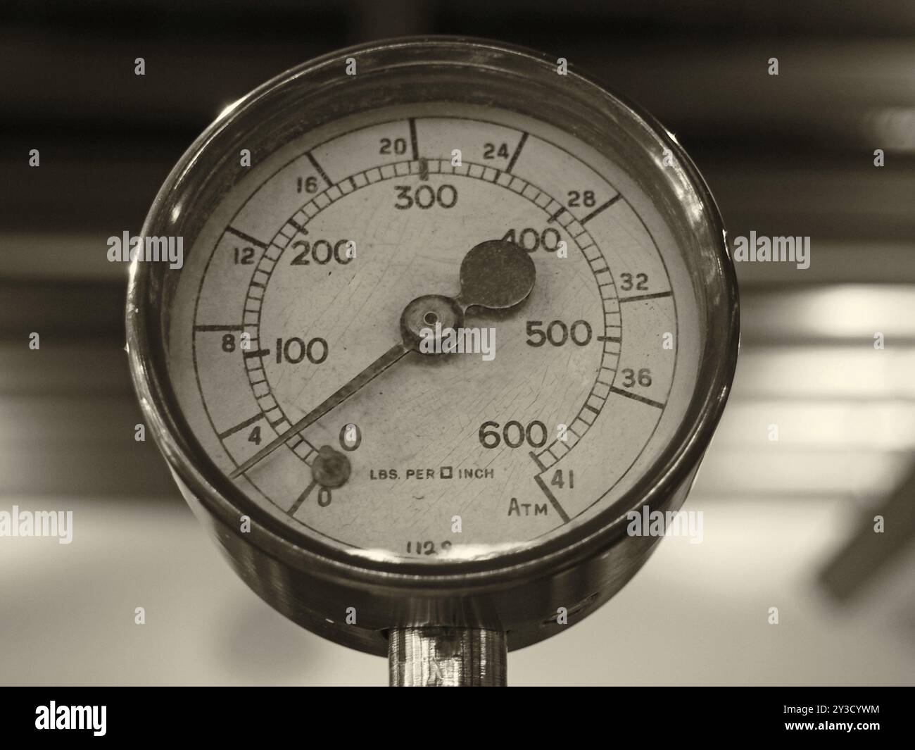 Sepia-Schwarzweißbild eines alten, glänzenden Messing-Rundmanometers mit einem runden Zifferblatt, das in Zahlen markiert ist Stockfoto