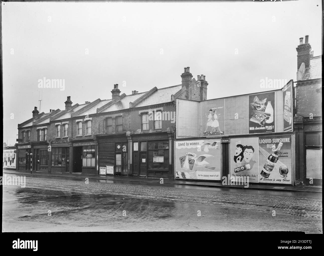 Außenansicht der Nummern 419-429 York Road, York Road, Southfields, Wandsworth, Greater London Authority, 1951; mit Werbetafeln, die Lücken auf der Terrasse schließen. Dieser Teil von Wandsworth erlitt während des Zweiten Weltkriegs eine Reihe von Bombenangriffen und es ist wahrscheinlich, dass die Werbetafeln Gebäude ersetzen, die während des Blitz verloren gegangen sind. Stockfoto