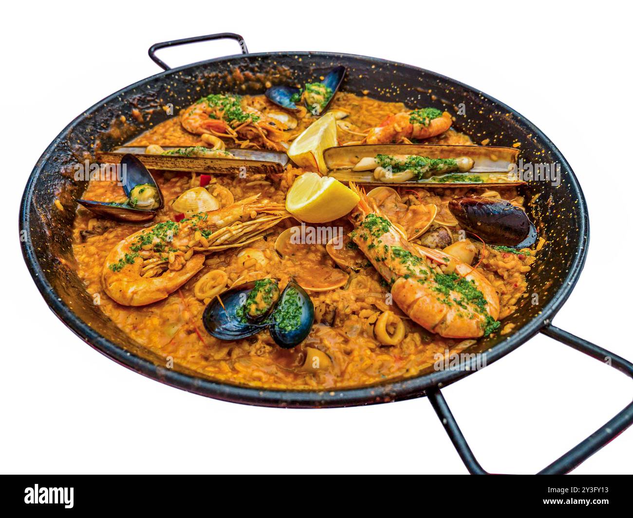 Das traditionelle spanische Meeresfrüchte-Gericht Paella in einer schwarzen Pfanne mit Muscheln und Garnelen auf einem Reisblock - isoliert auf weiß Stockfoto