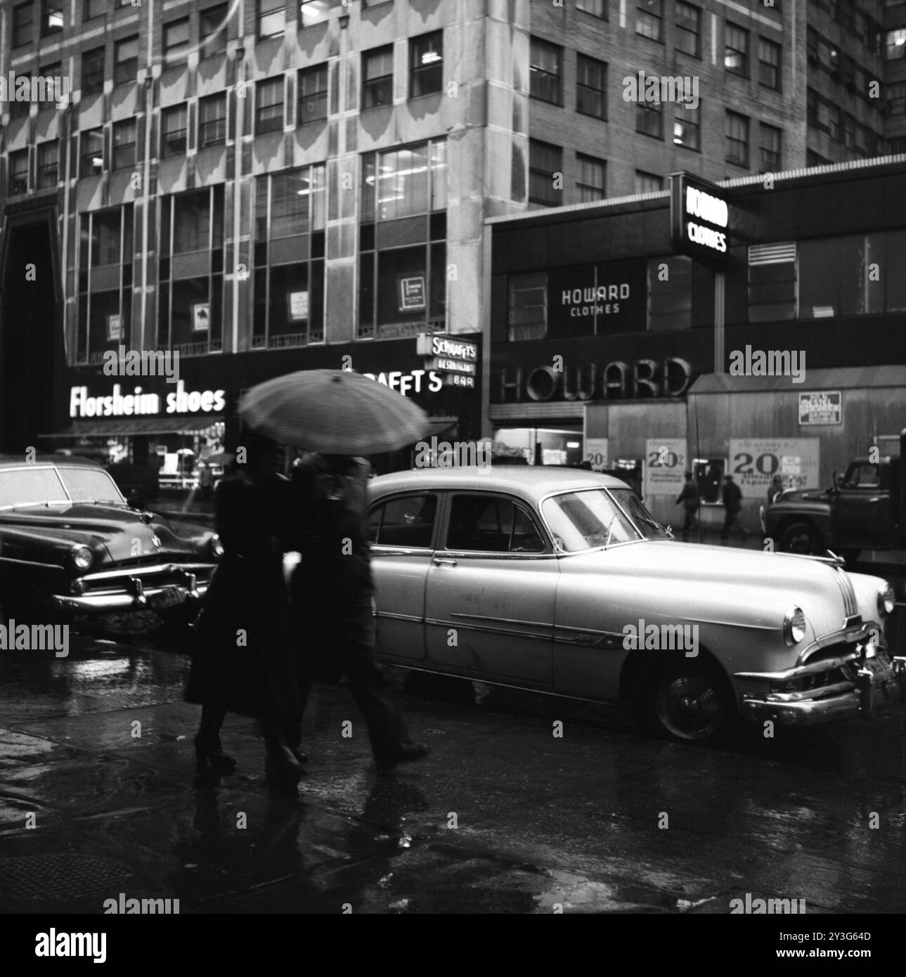 Fußgänger laufen auf der regnerischen 5th Avenue in New York City nahe der Kreuzung der 42nd Street und der New York Public Library. Stockfoto