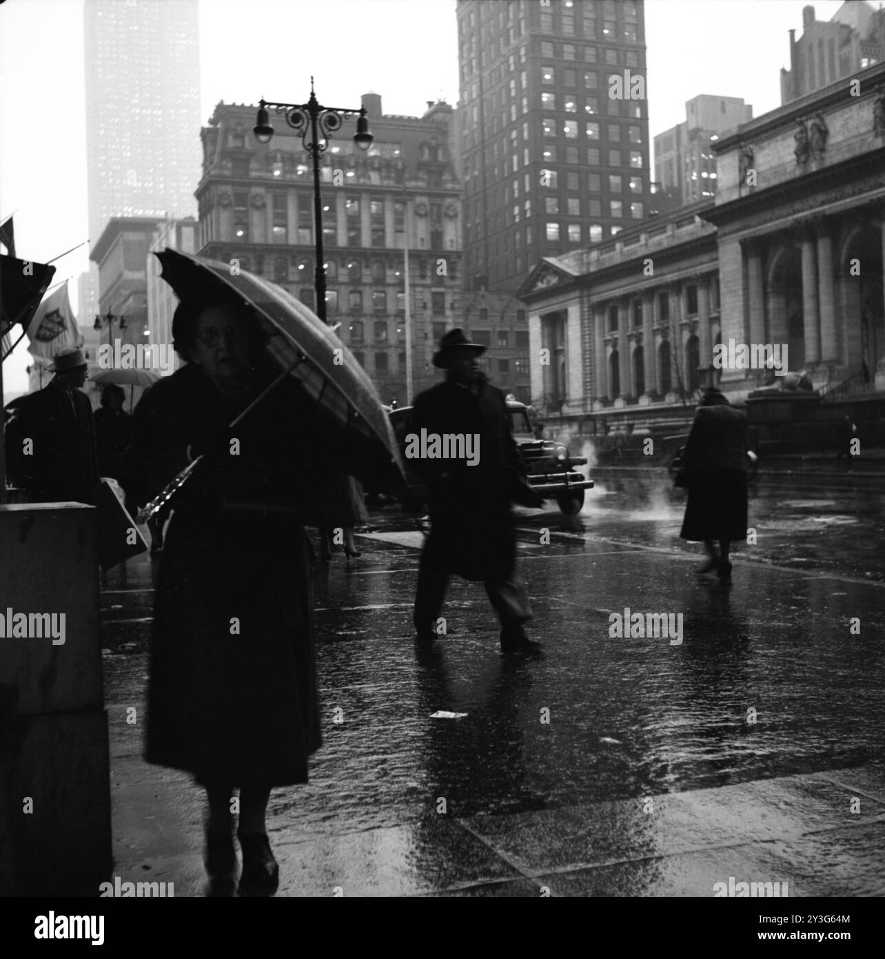 Fußgänger laufen auf der regnerischen 5th Avenue in New York City nahe der Kreuzung der 42nd Street und der New York Public Library. Stockfoto