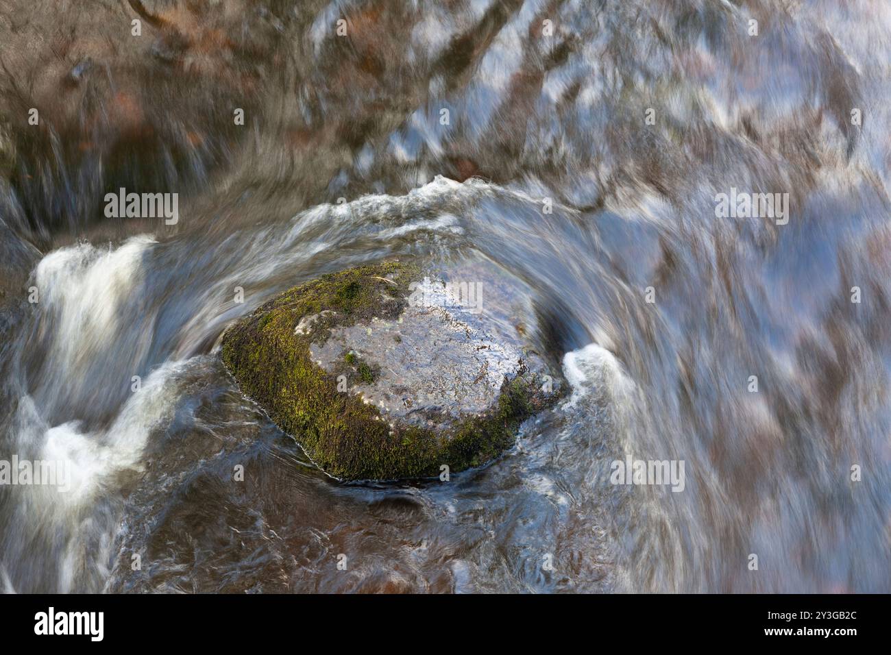 Schnell fließendes Wasser um einen Stein, River Tawe, South Wales. Stockfoto